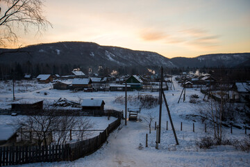 Russian village. Wooden huts with smoke from chimneys in the winter season