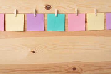 Colored notes hanging from a rope against wooden background