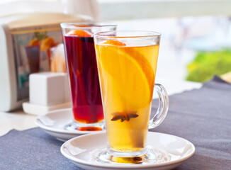 Mulled wine in tall glasses in a cafe. Warming drink with fruits and spices.