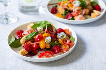 Summer panzanella salad with tomatoes, raspberries, basil and red onion