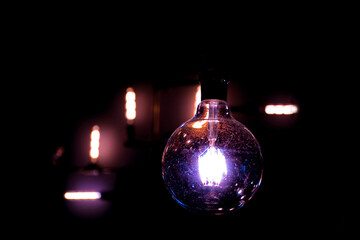 Closeup round light bulb with vintage electric lights on dark background