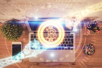 Blockchain theme hologram drawings over computer on the desktop background. Top view. Multi exposure. Concept of cryptoeconomy.