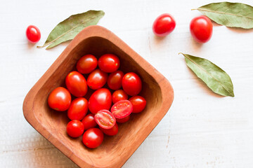 Naklejka na ściany i meble Close up shot of cherry tomatos in wooden bowl. Photographed on white background table