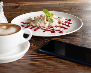 coffee cup, smartphone and dessert on wooden table