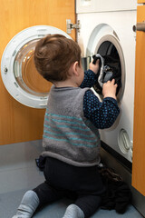 Child helping to set up the washing machine to do the laundry.