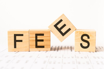 Wooden Blocks with the text: Fees. Fixed price charged for a specific service. Business and finance concept. Costs, charges, commissions, penalties. Cost, fee and taxes.