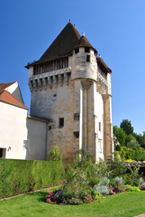 Fototapeta premium Ancient Stone Tower with Pointed Roof with Foreground Garden & Hedge against Blue Sky 