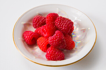 Raspberries on a plate on a white background.