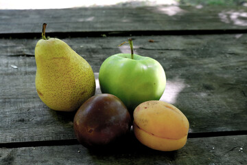 Fruit harvest. Fresh fruits. Apricot, plum, apple and pear on the background of an old rural wooden surface.
