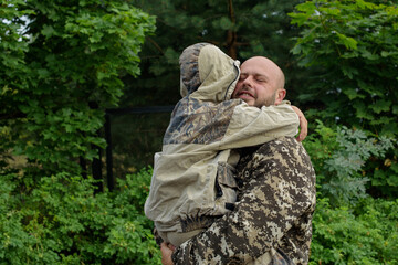 father and son in camouflage outside, father's day concept and greetings, laser tag military war game, father's return home