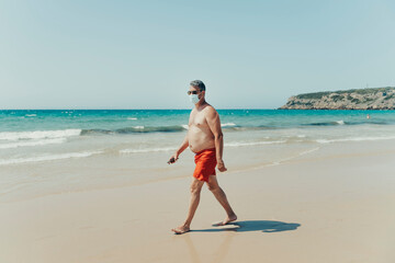 50-year-old man with sunglasses and a mask for the pandemic on the beach.