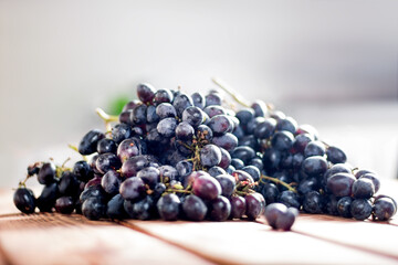 Bunches of fresh ripe red grapes on the surface with a wooden texture. Beautiful background with a branch of blue grapes in antique style. Red wine grapes.