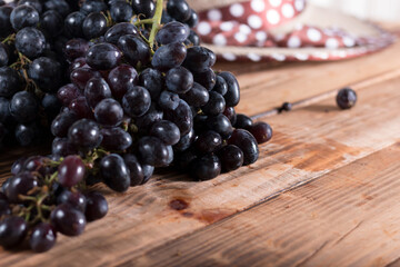 Bunches of fresh ripe red grapes on the surface with a wooden texture. Beautiful background with a branch of blue grapes in antique style. Red wine grapes.