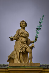 A fragment of the roof of a building with a sculpture of a woman holding a vine