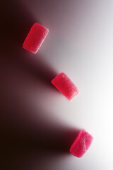 Close-up of red cube-shaped marmalade sweets on a white background with shadow.
