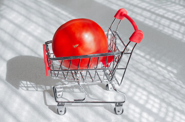 Concept of buying vegetables, ripe tomatoes in the grocery basket