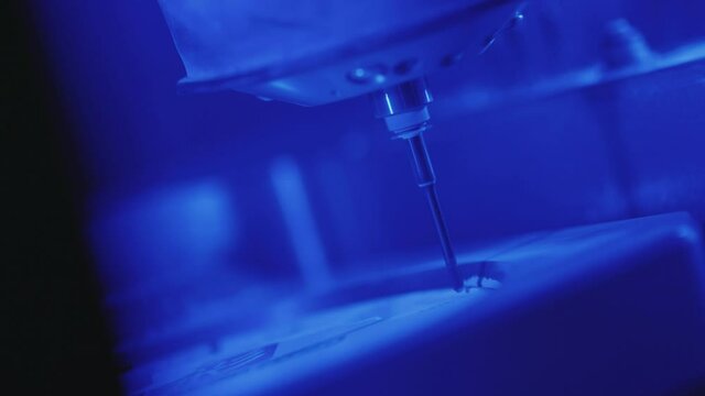 Slow motion works of the dental milling machine processing of carving out shape of human teeth from dental milling machine in blue light technician dentist construction close up