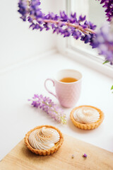selective focus. still life of green tea in a beautiful mug with cakes tart. nice breakfast. table setting with fresh flowers.