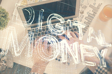 Double exposure of man's hands typing over computer keyboard and crypto currency theme hologram...