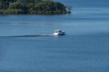 Recreational boat heading across calm lake on sunny morning