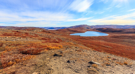 Autumn greenlandic orange tundra landscape with lakes and mountains in the background, Kangerlussuaq, Greenland