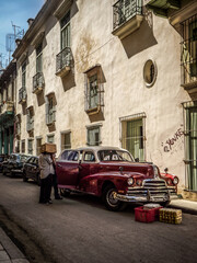 Men chatting on the street next to old red car in Havana, Cuba