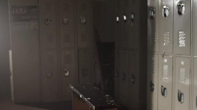 Establishing shot of empty changeroom, fighter walks into gym locker room with big duffle bag