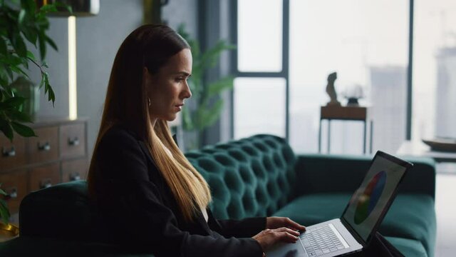 Businesswoman working on laptop at home office. Businessman walking in office