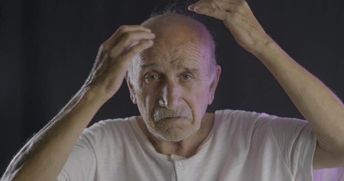 An old bald man is controlling his hair. Balding, lose hair concept.