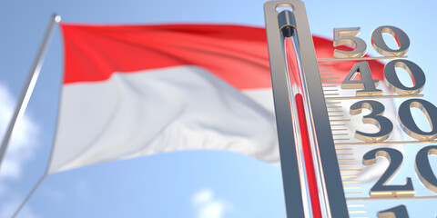 Thermometer shows high air temperature against blurred flag of Indonesia. Hot weather forecast related 3D rendering