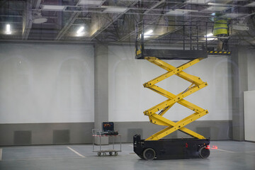 Electrician works stand on electric hoist ( lifting mechanism) and mending ceiling lights. Car...