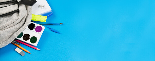 Dropped school supplies from a backpack on a blue background.