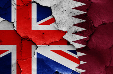 flags of UK and Qatar painted on cracked wall