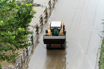 Due to the flood, mud piled up on the riverside bike paths is being cleaned up with skid loader