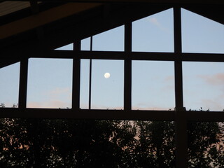 Distant moon on blue sky through window