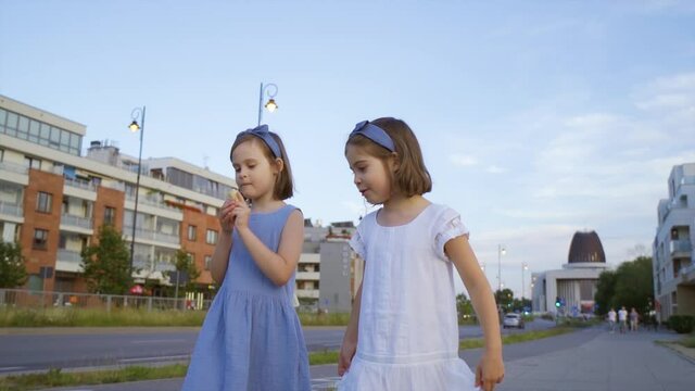 two cute little girls walk around the city and eat ice cream