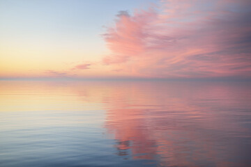Baltic sea after the rain at sunset. Dramatic sky with glowing  pink clouds, symmetry reflections...