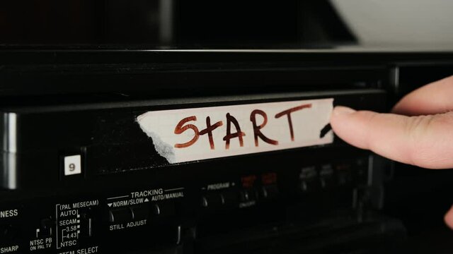 male hand inserts VHS videotape into old vintage dusty VCR record player. The inscription on cassette START. Then man takes out videotape from tape recorder.