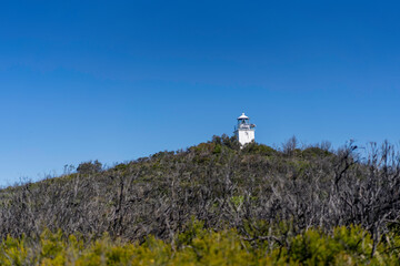 lighthouse on a hill with a beautiful blue sky in the background