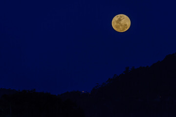 Fototapeta na wymiar Full moon over the silhouette of the hills