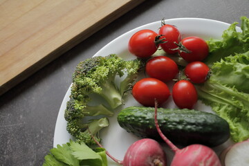 Fresh vegetables in a white plate on a gray table