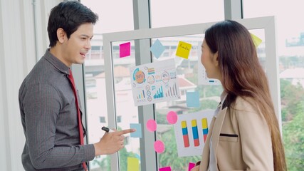Business people work on project planning board in office and having conversation with coworker...