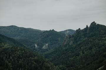 Gloomy view to great mountains under dark gray cloudy sky. Dramatic  landscape with  mountains in rainy weather. Atmospheric scenery with giant mountain ridge in overcast darkness.