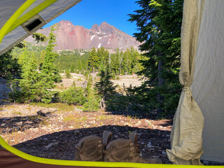 A large volcanic mountain peak is framed by the entryway of a small backpacking tent.