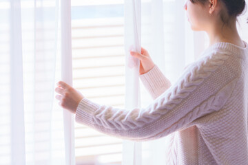 カーテンを開ける若い女性