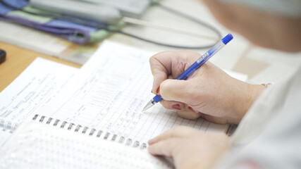 Lab researcher writing research report. Female researcher in lab. Closeup of lab scientist hand writing notes. Woman hand writing science report