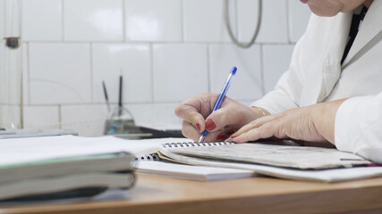 Lab researcher writing research report. Female researcher in lab. Closeup of lab scientist hand writing notes. Woman hand writing science report