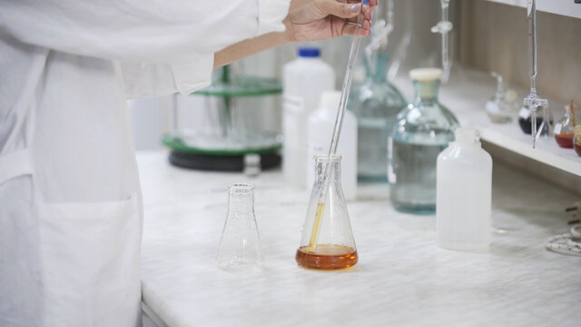 Female scientist with pipette analyzes liquid in distillery laboratory researcher. Analysis of whiskey sample on laboratory equipment. - Powered by Adobe