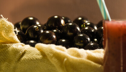 Fresh fruit and glass of jaboticaba juice on a reddish background