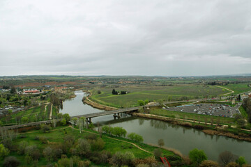 Countryside landscape. Aerial view of the road and bridge  over the River Tajo in Toledo, Spain. The green fields, grass and meadow under a cloudy sky. 